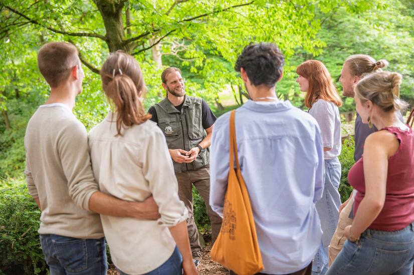 Gruppe mit Pfleger Eine Gruppe Menschen steht vor einem Mann mit Zoo-Weste und hören gebannt zu