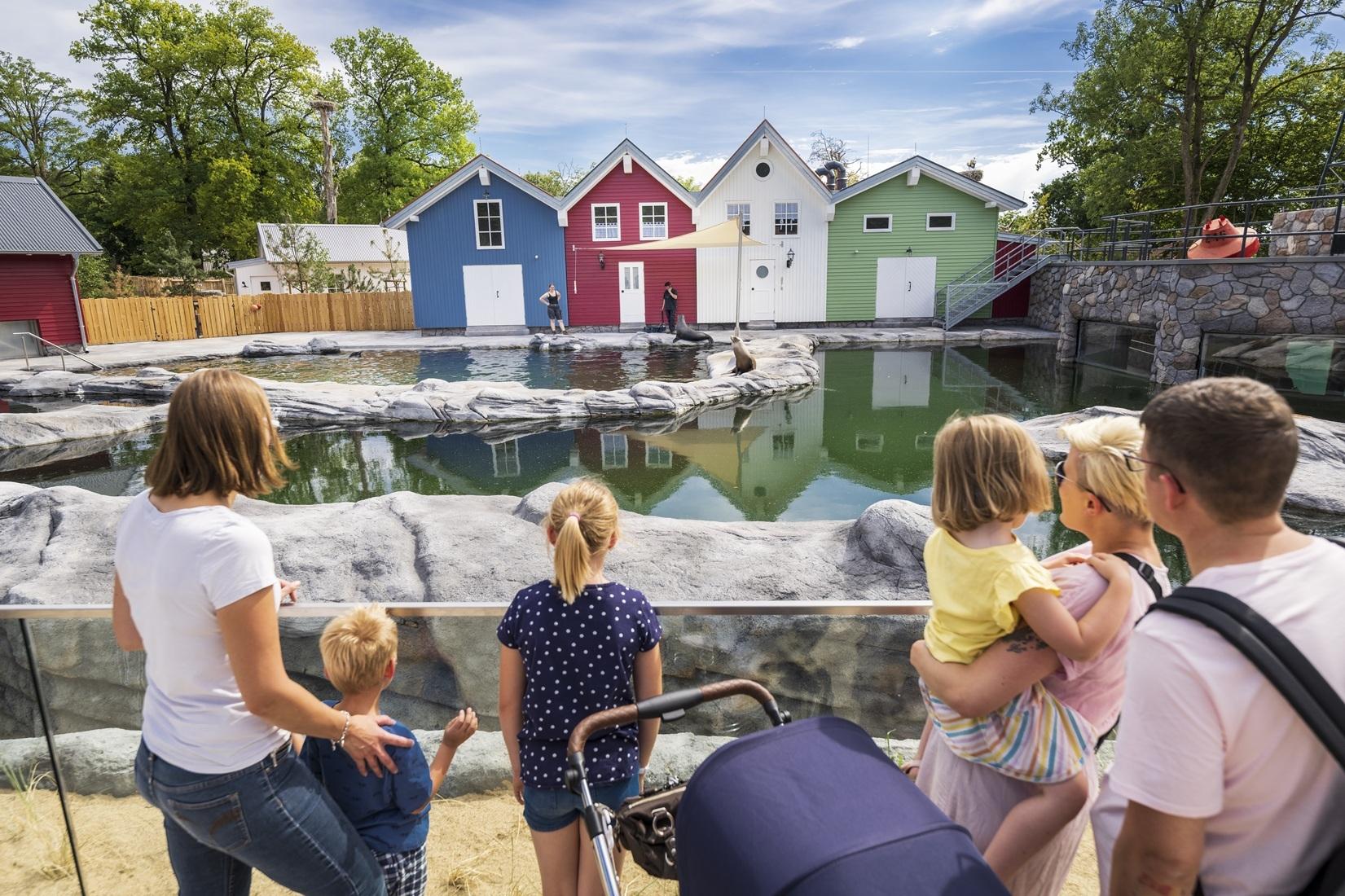 Wasserwelten im Zoo Osnabrück Eine Familie steht vor einem großen Wasserbecken. Im Hintergrund stehen bunte Häuser.